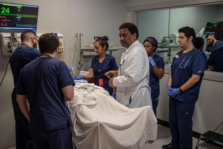 Students doing work in simulation lab with professor
